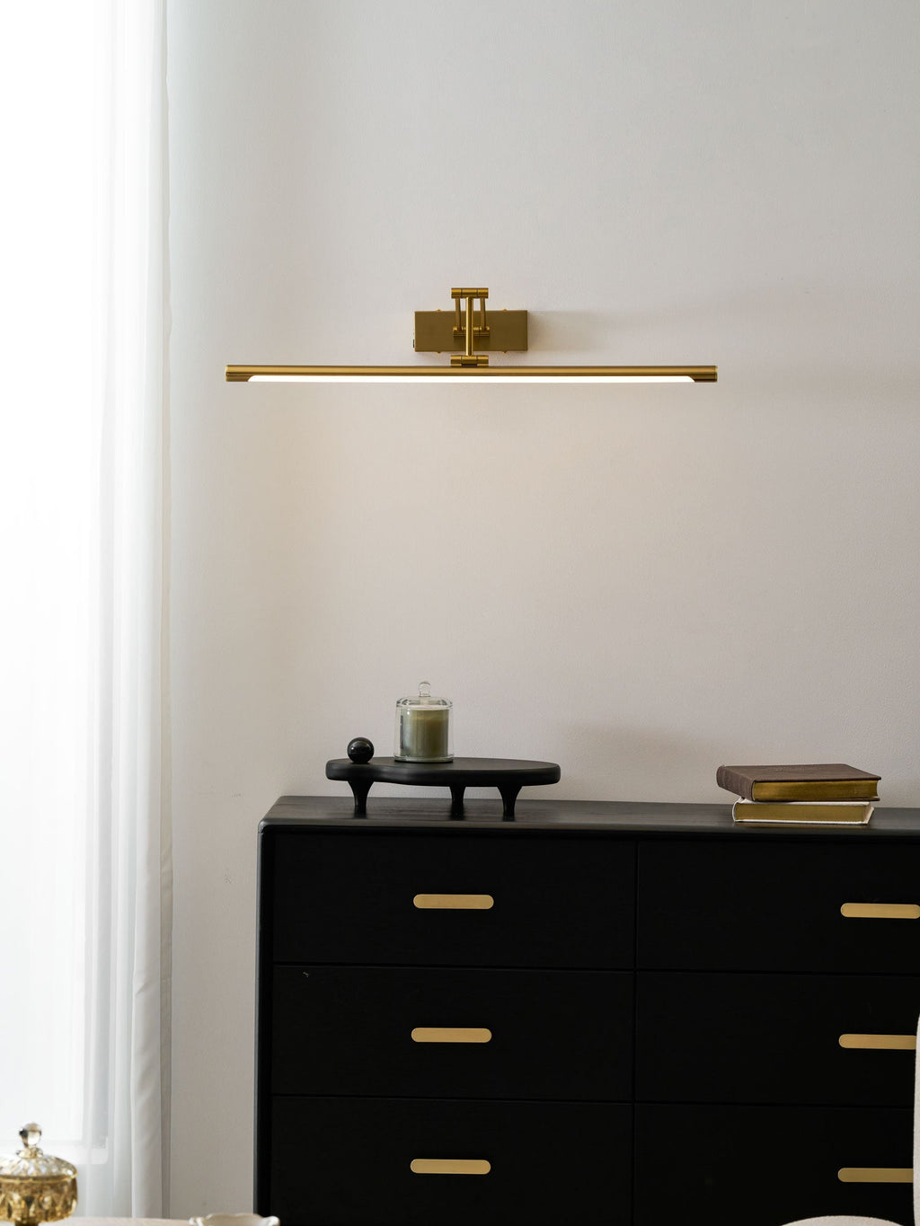 Picture light in gold reaching over a deep artwork frame