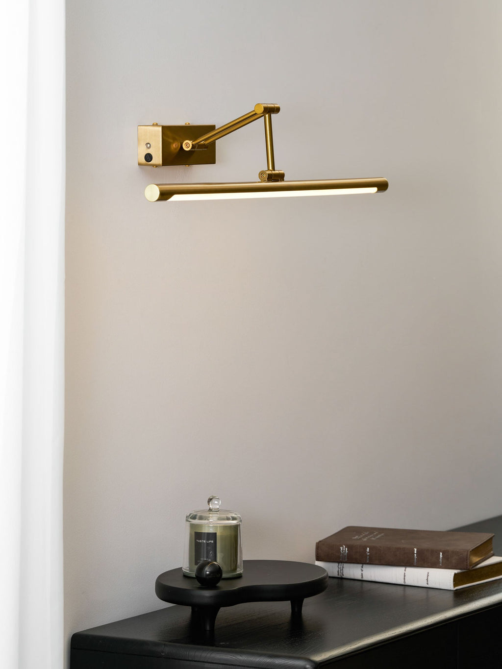 Gold frame light illuminating a painting in a quiet hallway