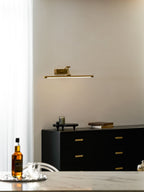 Slim gold wall light casting an even warm wash on artwork