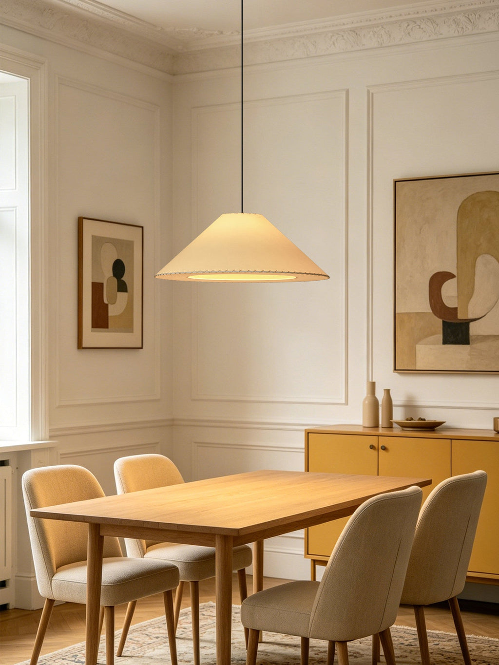 This white Clérachic cone pendant hangs in a panel-moulded dining room lined with framed artwork.