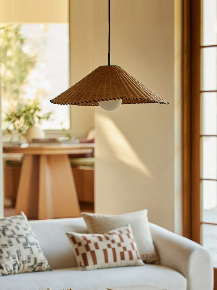 Near a doorway to a round table, this lit Clérachic pendant hangs above a patterned-pillow sofa.