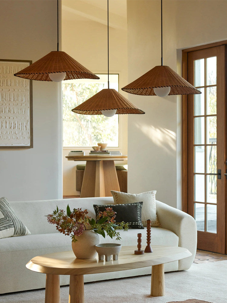Two sizes of this Clérachic pendant hang lit above a coffee table, with a dining table visible beyond.