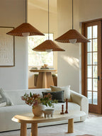 Two sizes of this Clérachic pendant hang lit above a coffee table, with a dining table visible beyond.