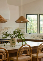 Two sizes of this Clérachic pendant hang lit above a marble counter set with a vase of greenery.