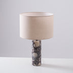 Clérachic marble table lamp turned to a three-quarter angle on grey, showing the drum shade's curve from the side.