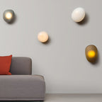 Pebble glass wall lamp lit warmly against a neutral wall