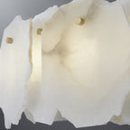 Macro of the alabaster plates, their veining and rough cut edges caught by a small brass pin