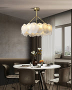 Burton chandelier lit above a white oval dining table in a city apartment with a window view