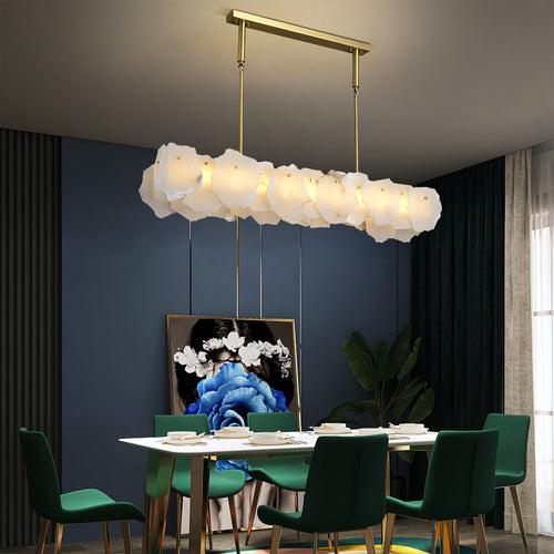 Linear Burton chandelier over a rectangular dining table set with green velvet chairs
