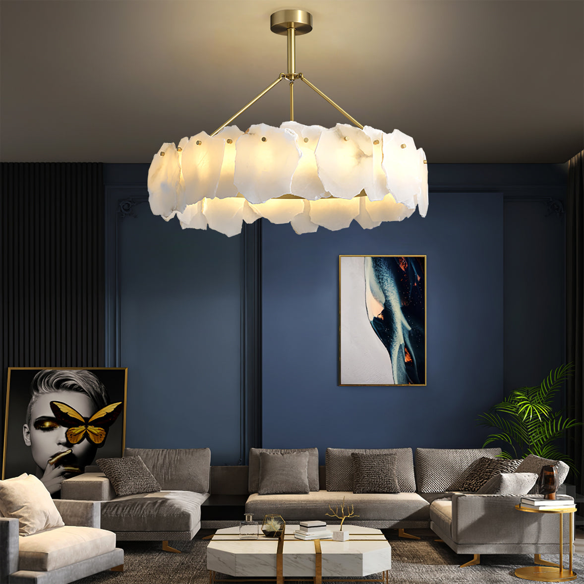 Burton chandelier lit over a grey sectional in a navy living room with framed art