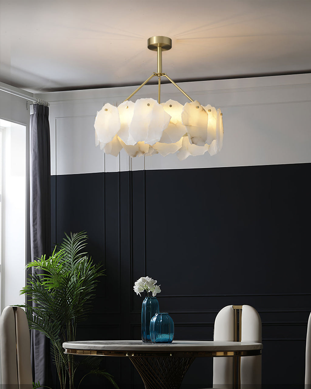 Burton chandelier over a round marble dining table against a navy panelled wall