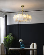 Burton chandelier over a round marble dining table against a navy panelled wall