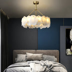 Burton chandelier glowing above a bed in a navy and charcoal bedroom