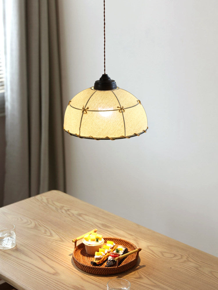 This Clérachic pendant hangs low and lit above a small dessert plate on a light-wood table.