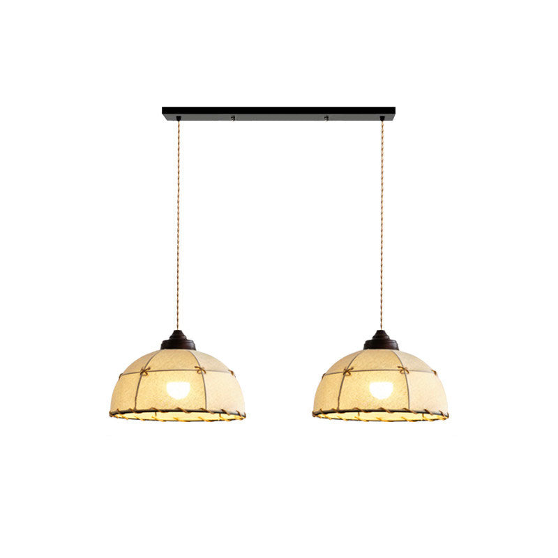 Two of these Clérachic pendants hang side by side from a linear plate, shades lit against a plain backdrop.