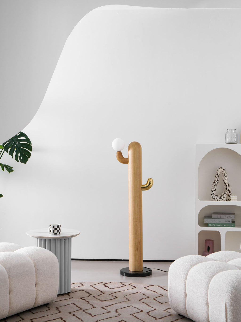 Clérachic wood floor lamp shown in a tighter crop, its glass globe bulb unlit on the brass hook beside a round side table.