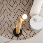 Clérachic floor lamp base set on a diamond-patterned rug, the glass globe glowing warm beside the marble-topped side table close by.
