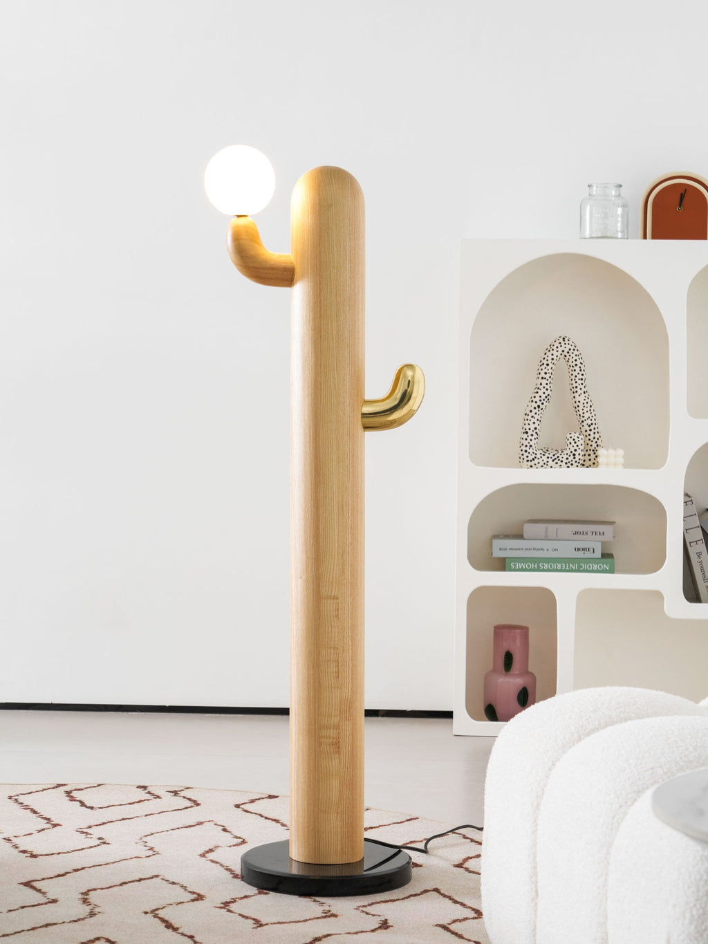 Clérachic floor lamp in close crop, showing the wood grain of the curved column and the brass hook holding its glowing glass globe.