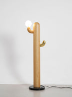 Pale-wood Clérachic floor lamp with a lit glass orb, full length on a grey studio background with the cord visible.