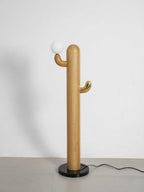 Pale-wood Clérachic floor lamp with a lit glass orb, shown full length on a plain grey studio background.
