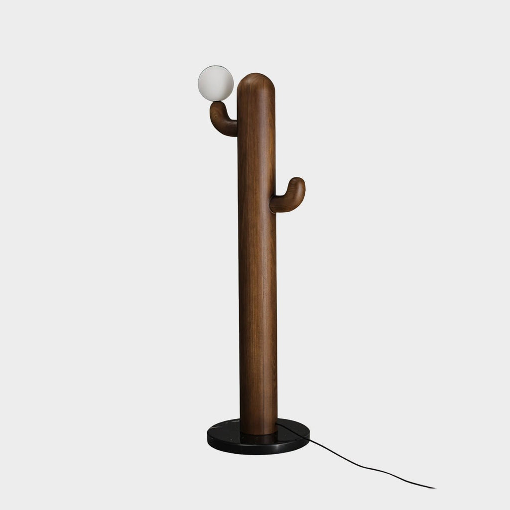 Walnut-toned Clérachic floor lamp with its glass orb lit, photographed on a plain grey studio background with cord visible.