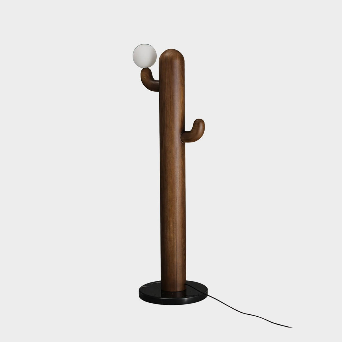 Walnut-toned Clérachic floor lamp with its glass orb lit, photographed on a plain grey studio background with cord visible.