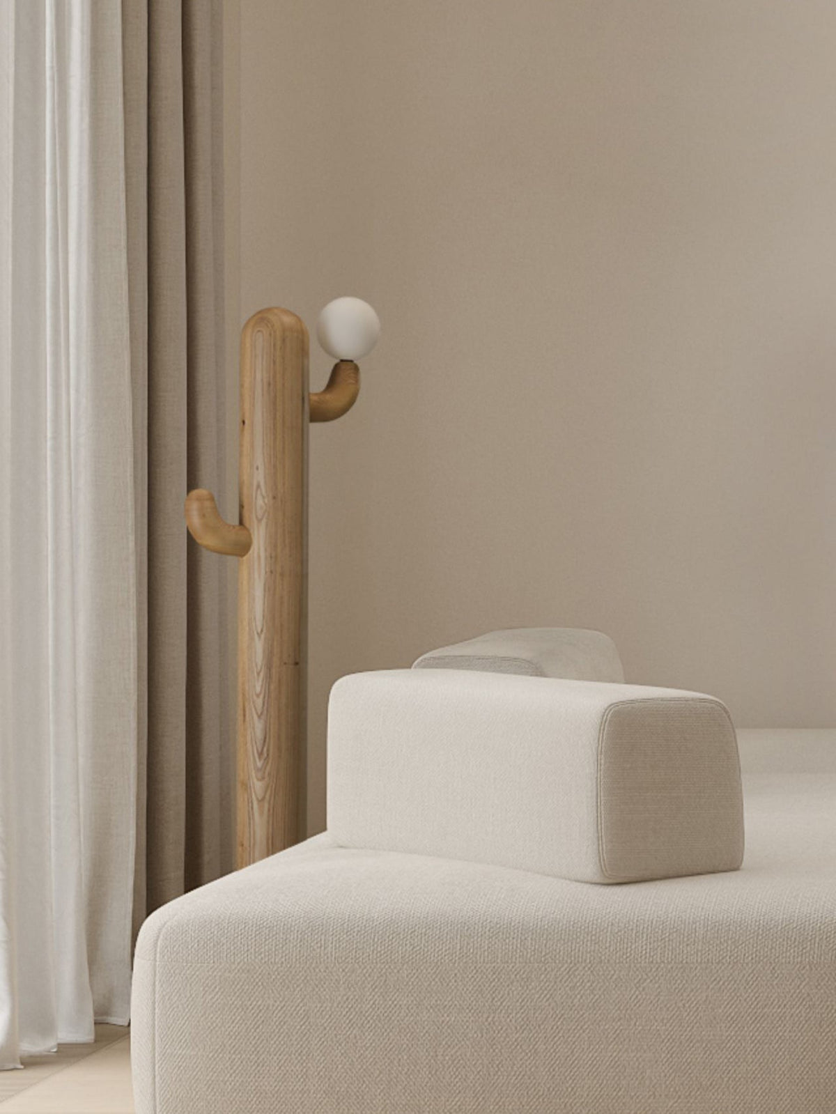 Pale-wood Clérachic floor lamp lit beside a cream sofa and ottoman near a sheer curtain in bright daylight.