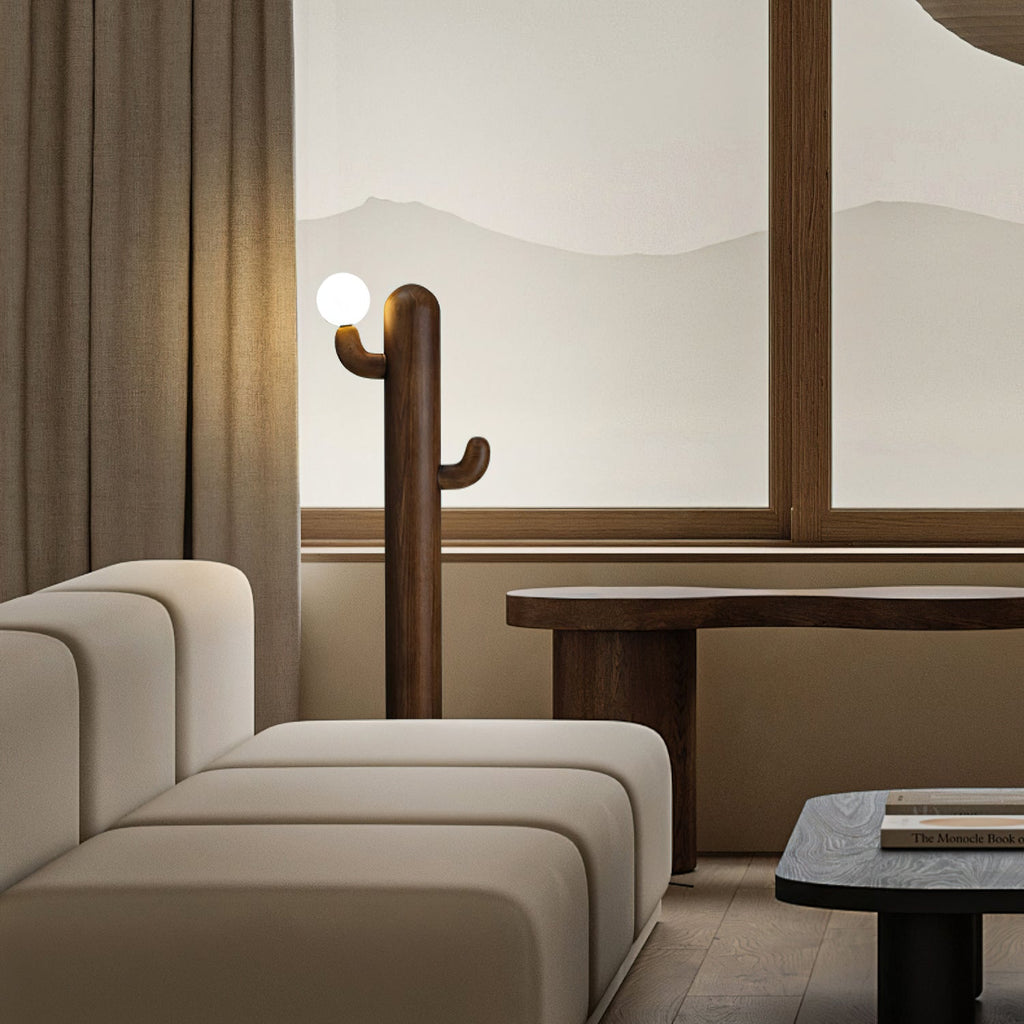 Walnut-toned Clérachic floor lamp lit against a mountain-print curtain backdrop beside a low wood bench.