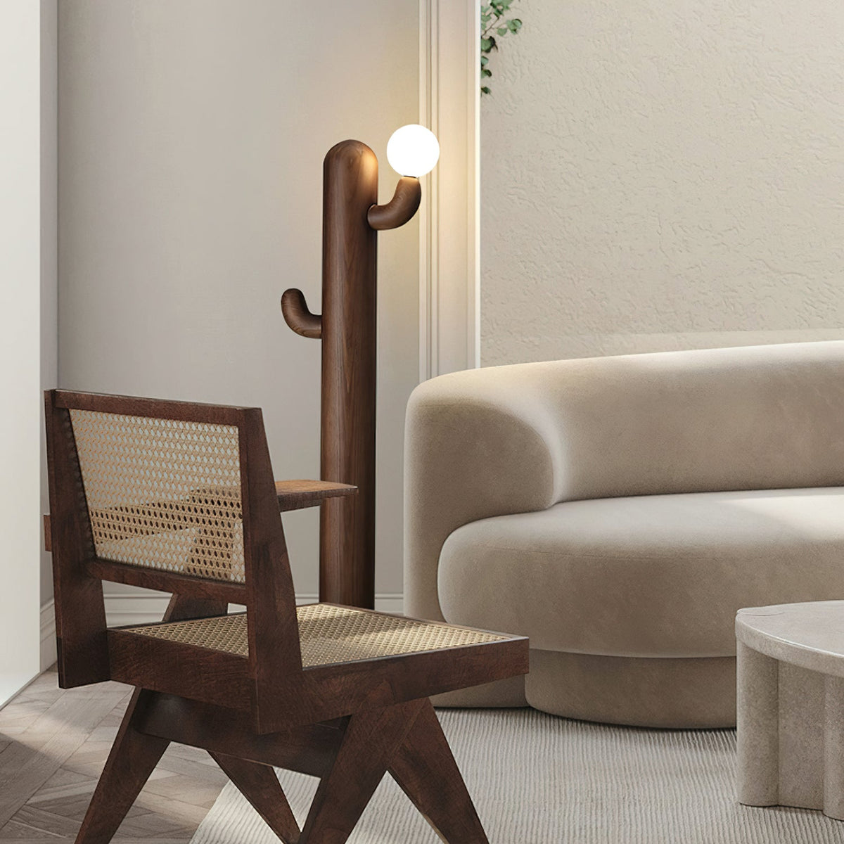 Walnut-finished Clérachic floor lamp stands lit beside a rattan-seated wood armchair and a curved cream sofa.