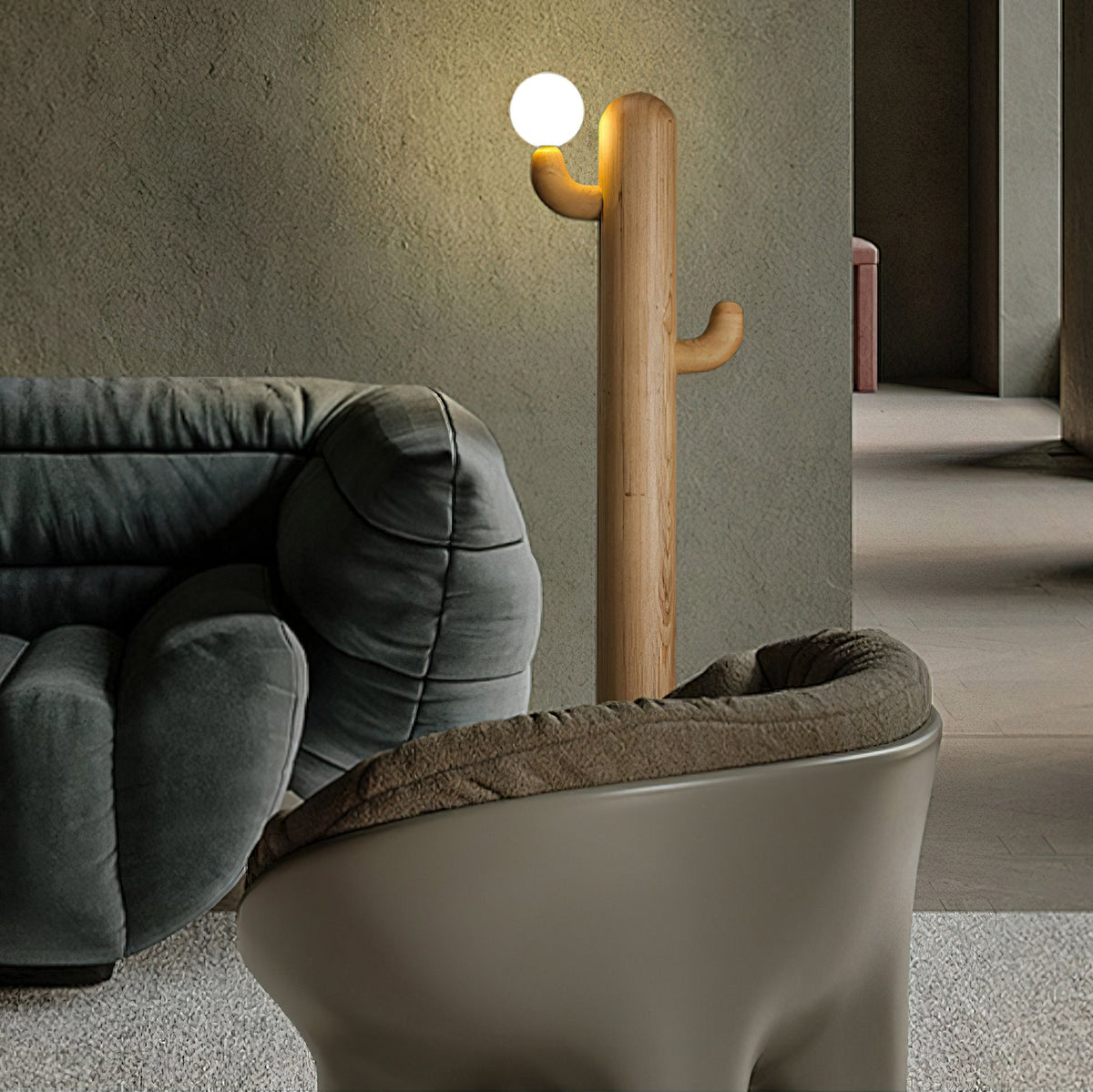 Light wood Clérachic floor lamp lit beside a green velvet sofa and armchair, set against a muted pink wall accent.