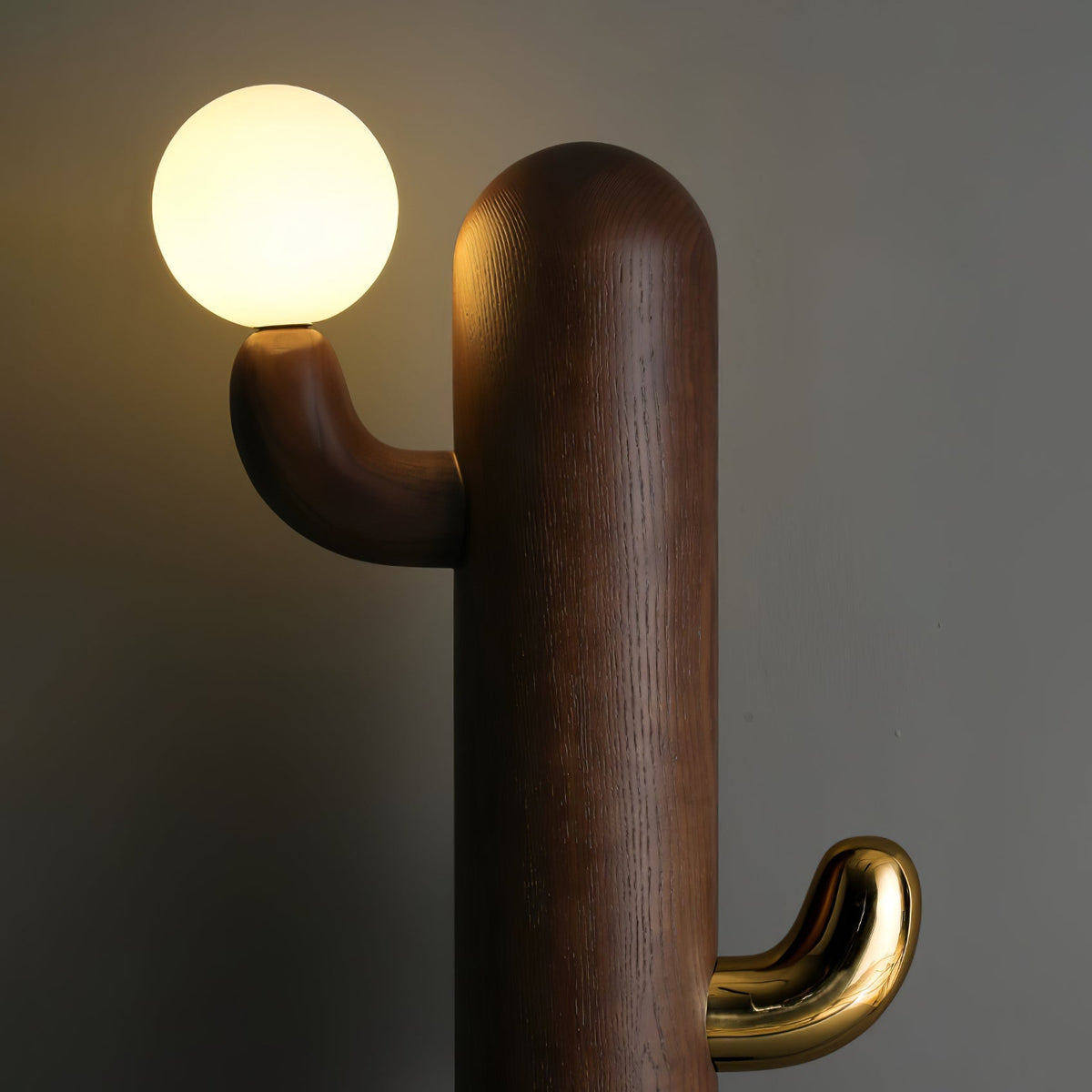 Close-up of a walnut-toned Clérachic floor lamp shows the wood grain cradling the glass orb, brass hook beneath.