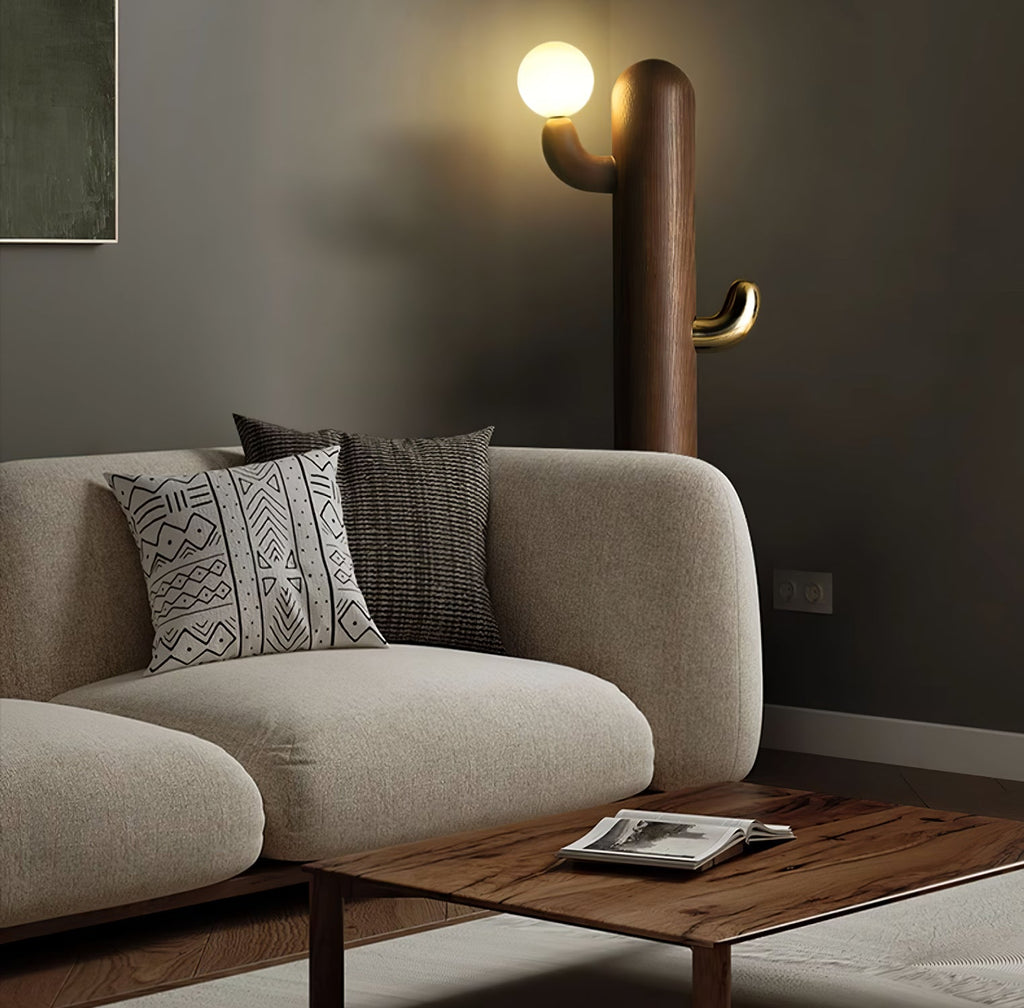 Dark wood Clérachic floor lamp lit beside a beige sofa with patterned cushions, seen from a closer angle.