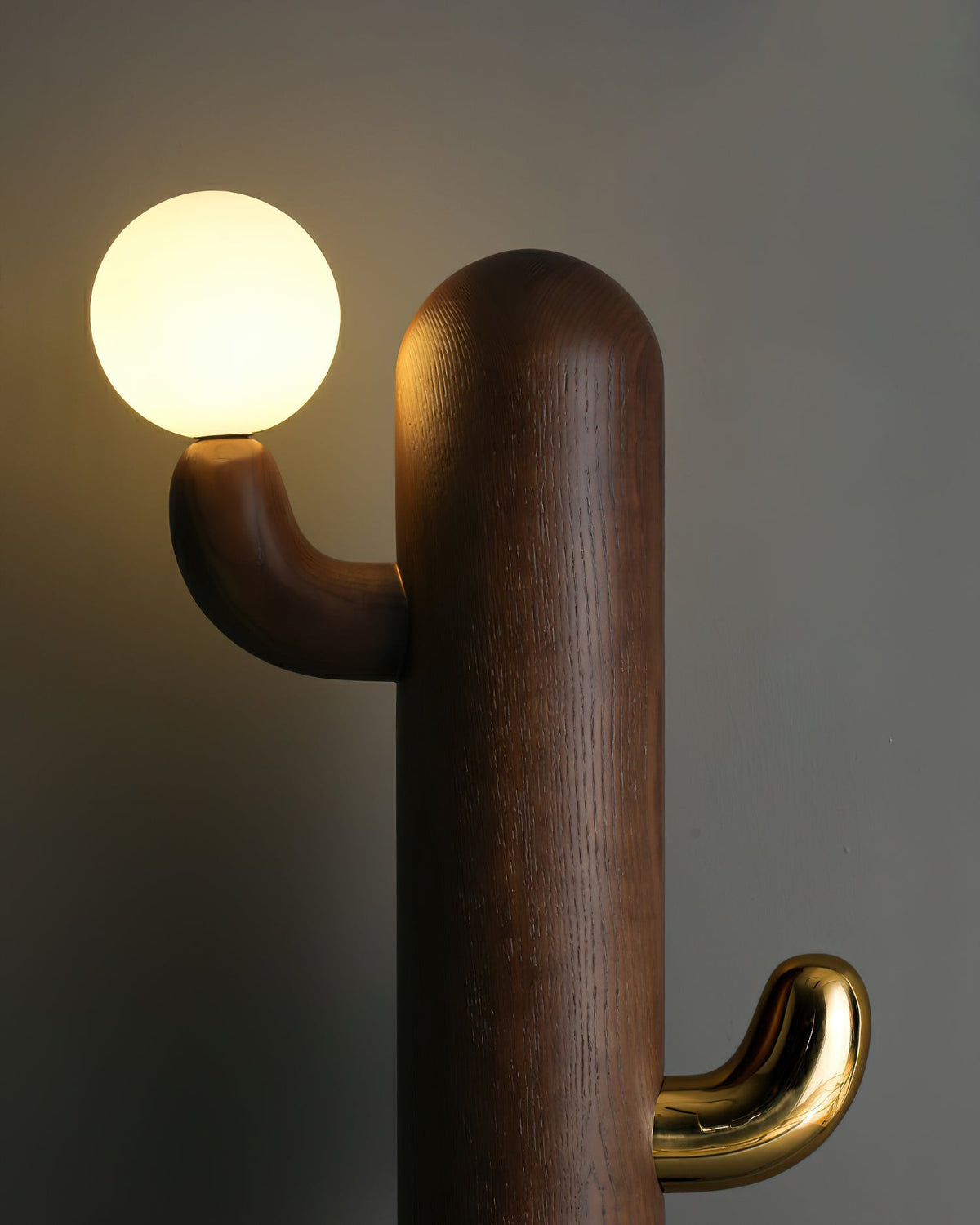 Close-up of a walnut-toned Clérachic floor lamp shows the wood grain, the glass orb bulb and a brass hook below it.