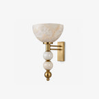 Photographed alone in brushed brass, this Clérachic sconce pairs a bowl-shaped alabaster shade with a two-rod arm.