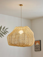 In a room corner, this Clérachic pendant hangs beside a framed sun-motif artwork and a trailing fern leaf.