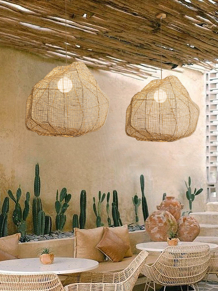 Two of this Clérachic pendant hang under a thatched pergola roof near a display of potted cacti.