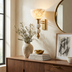 In an entryway, this brass Clérachic sconce glows beside a console holding a vase of olive branches.
