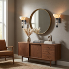 A matte-black pair of Clérachic sconces frames a round mirror above a console with dried grasses and a sculpture.