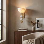 This brass Clérachic sconce lights a corner beside a console set with books and a stoneware vase.