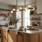In a kitchen with hanging copper pots, the matte-black Clérachic chandelier glows above a marble island.