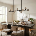 The matte-black Clérachic chandelier lights a dark wood table set with florals against cream wainscoting.