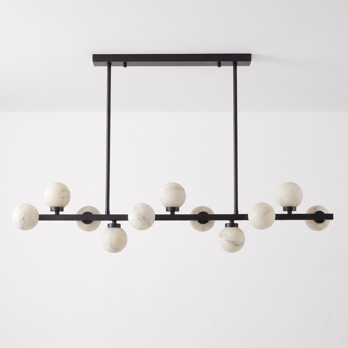 This Clérachic chandelier in matte black is shown on a plain backdrop, its balls staggered along the bar.