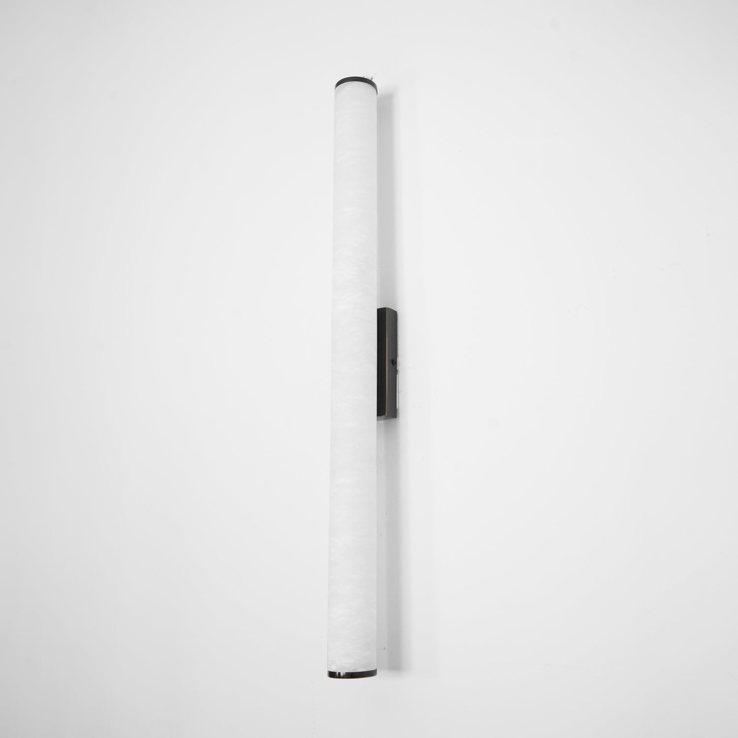 Slim alabaster wall sconce with brass finish against pale wall