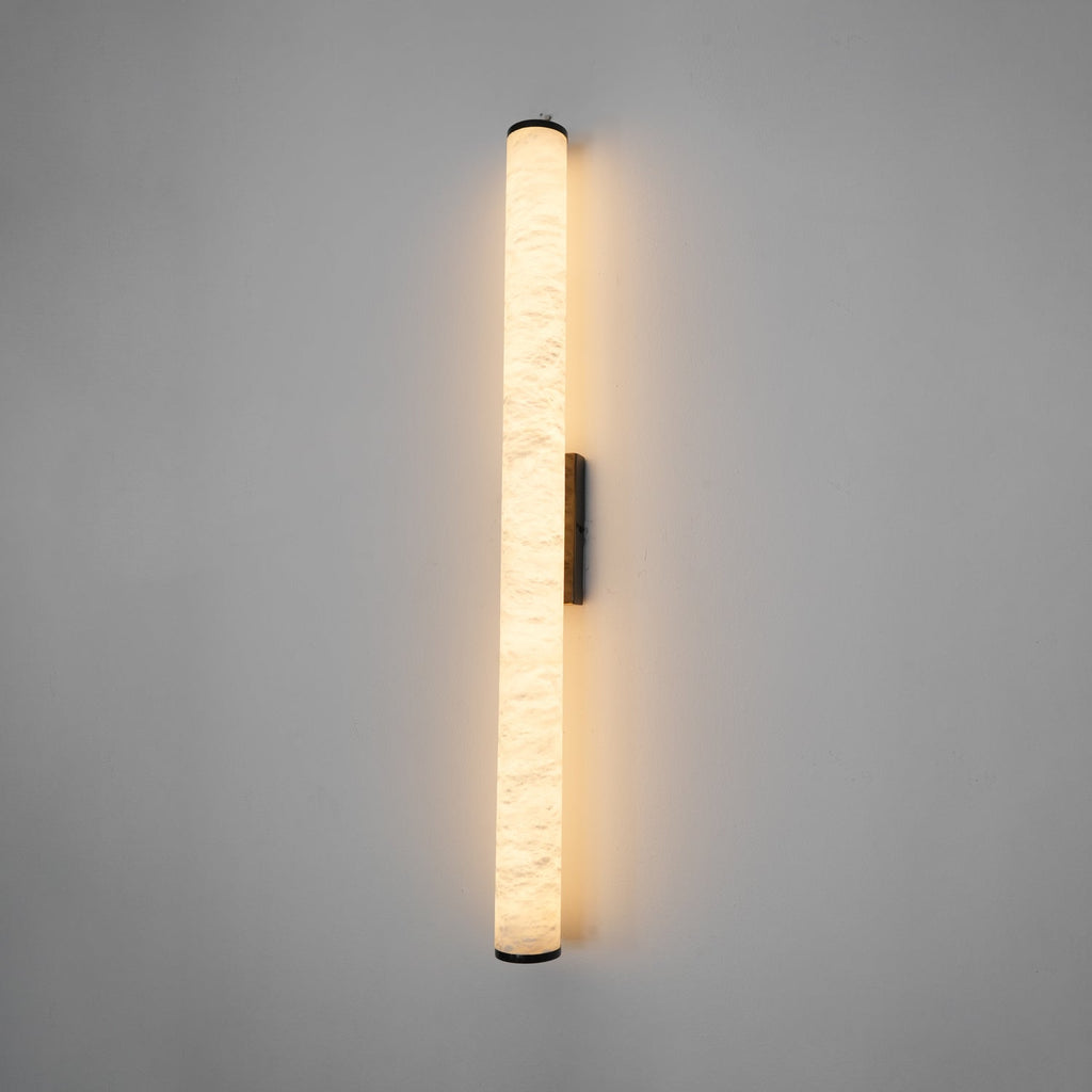 Slim alabaster wall sconce mounted beside a doorway