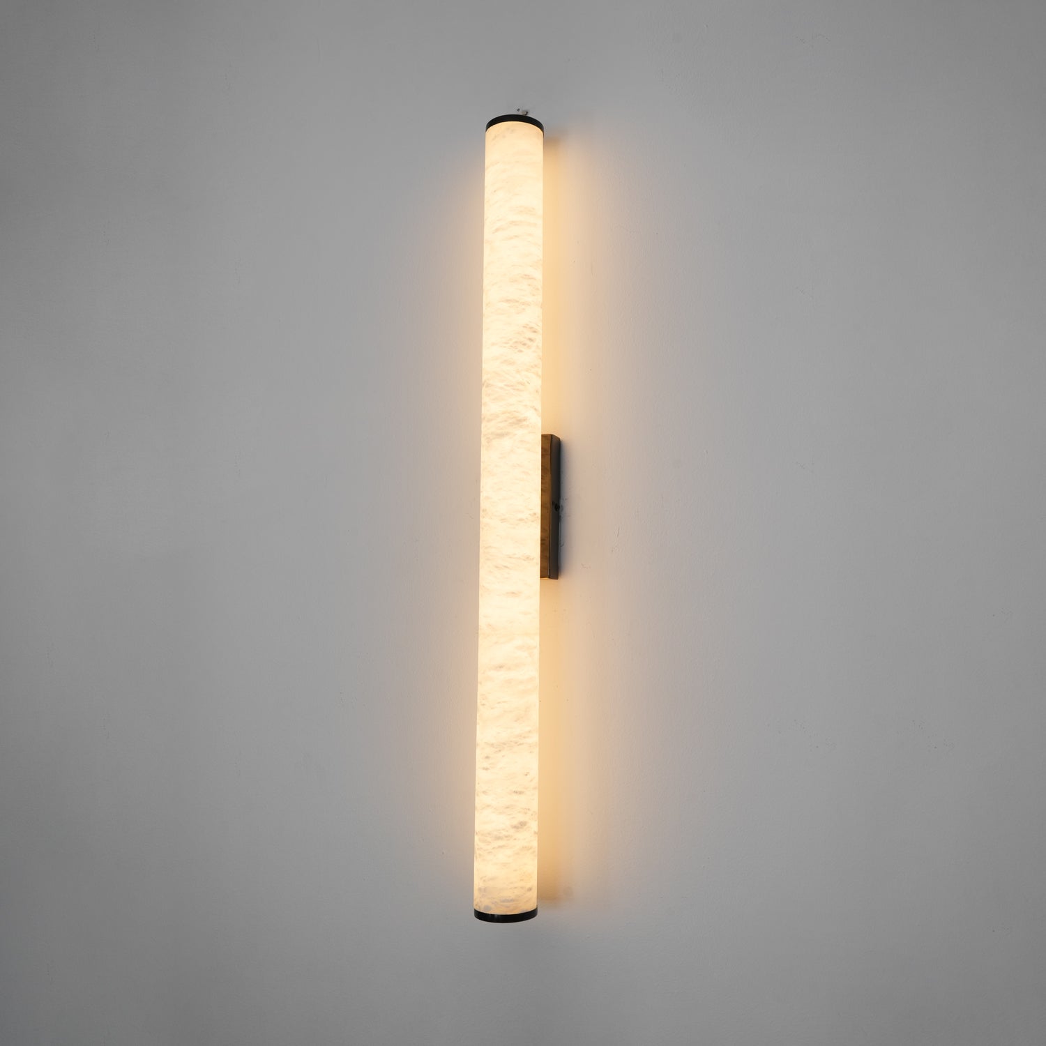Slim alabaster wall sconce mounted beside a doorway