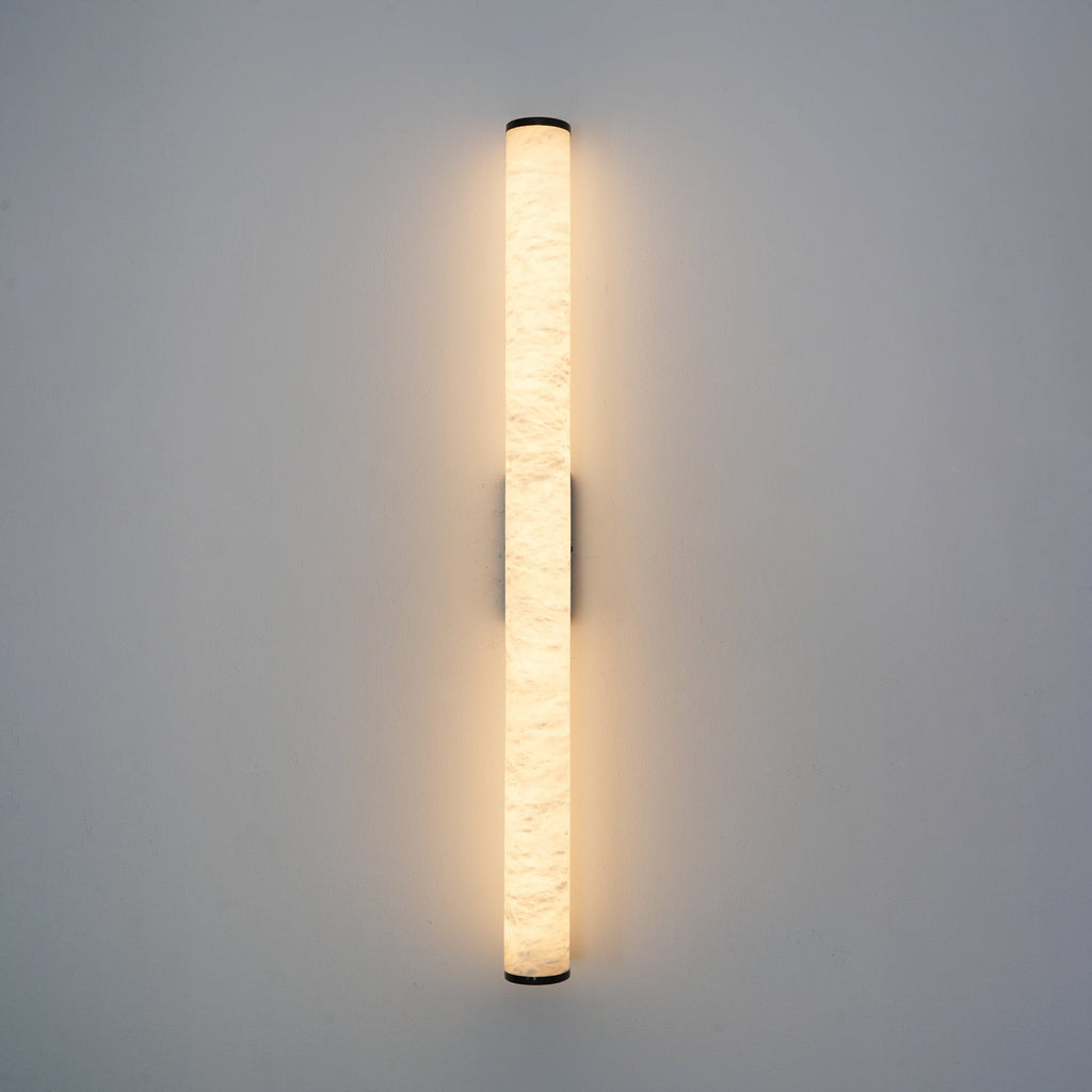 Brass wall sconce with glowing alabaster shade in soft focus