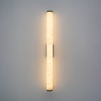 Brass wall sconce with glowing alabaster shade in soft focus
