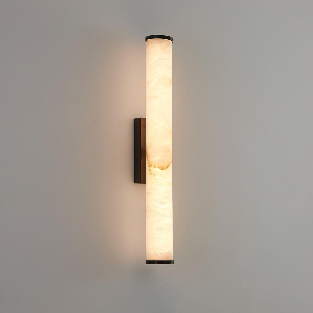 Brass wall sconce with veined alabaster shade casting soft uplight