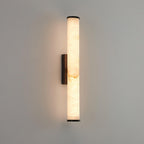 Brass wall sconce with veined alabaster shade casting soft uplight