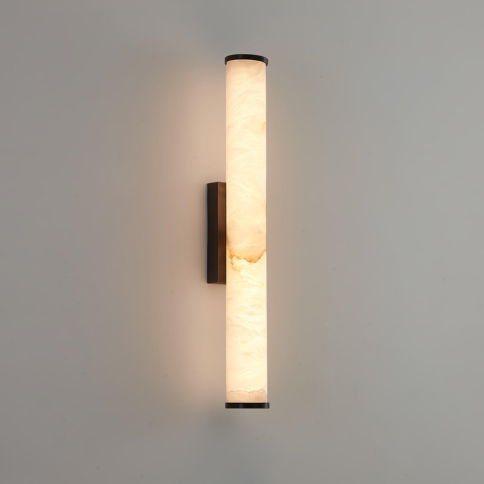 Brass wall sconce with veined alabaster shade casting soft uplight
